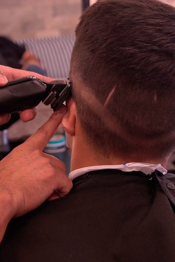 Corte degradê com um risco desenhado na lateral, feito com máquina na Barbearia Constant