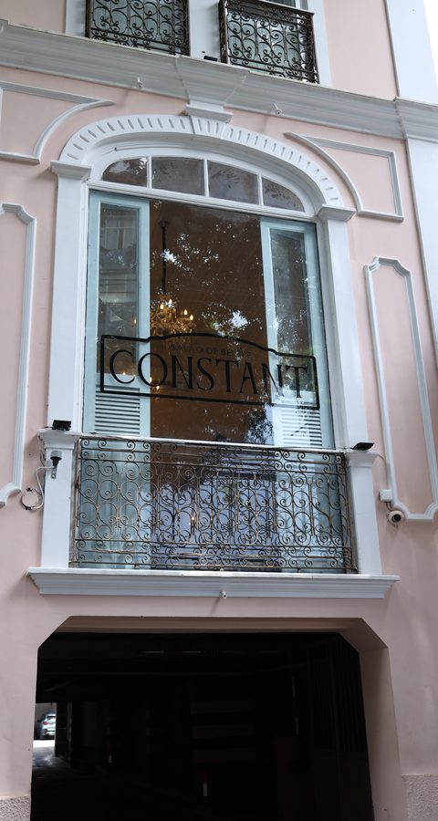 Fachada rosa do casarão do Constant Benjamin, com o nome Constant na janela em arco e a varanda de ferro trabalhado