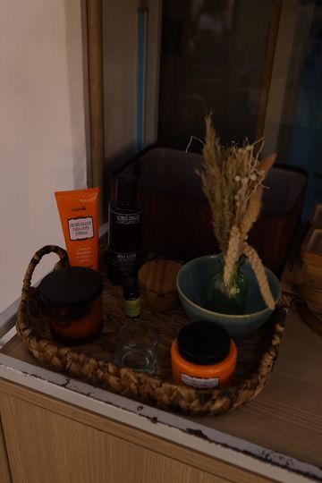 Cesta com produtos de cabelo e flores secas sobre um móvel de madeira no Constant Museu